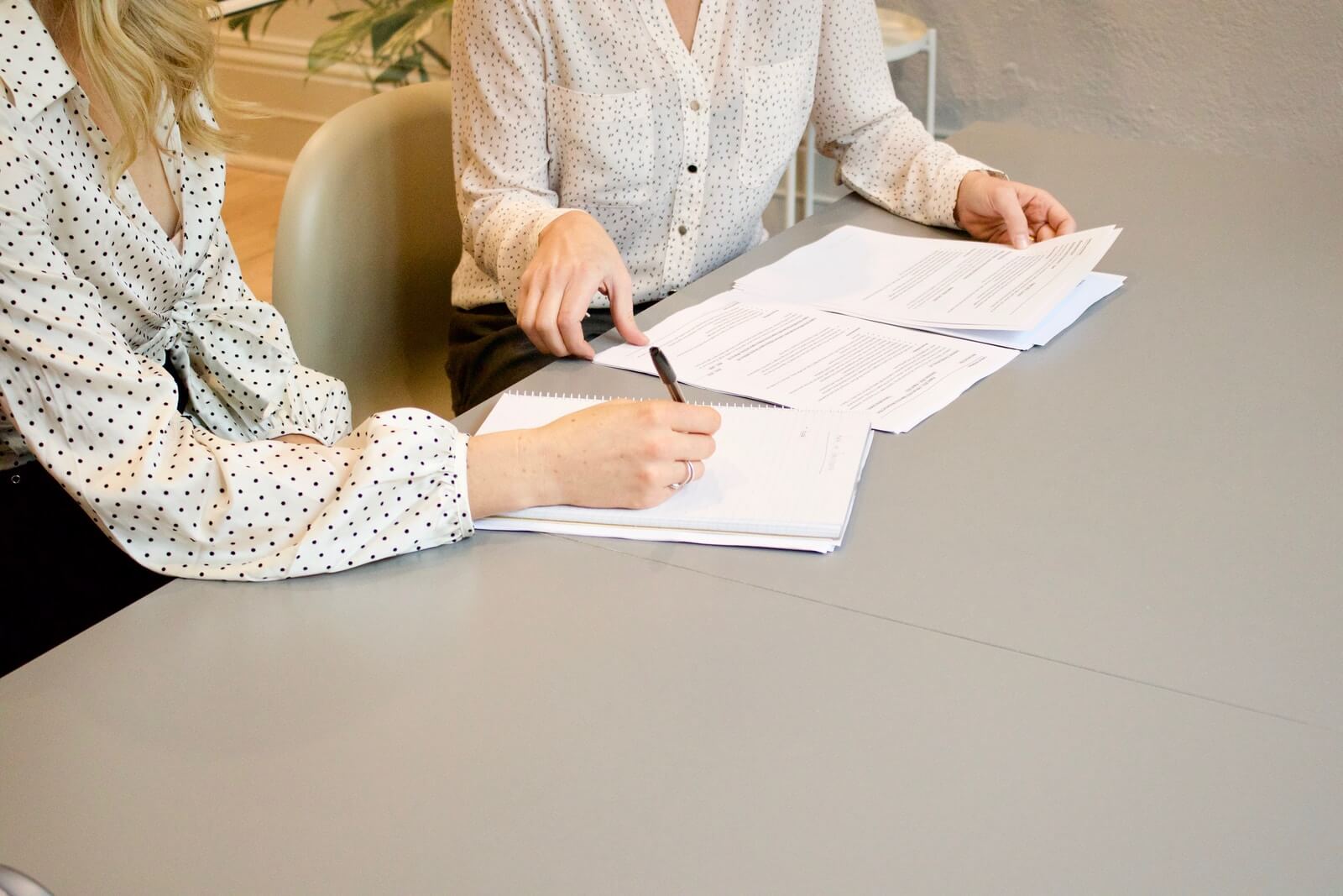 Foto von Gabrielle Henderson woman signing on white printer paper beside woman about to touch the documents